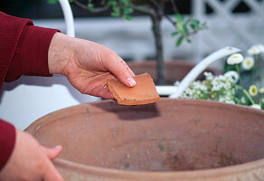 Putting a piece of clay on the drainage hole