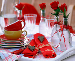 Rosa (rote Rosen) in Glasflaschen mit herzförmigen Namensschildern