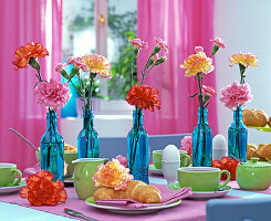 Breakfast table with Dianthus (carnation) in blue bottles