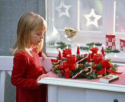 Mädchen bewundert Adventskranz mit Juniperus (Wacholder), Abies