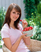 Young woman eats Prunus avium (sweet cherries)