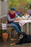 Grandfather sitting at table with dog peeling Malus (apples)