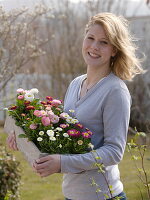 Young woman with bellis (common cosmos) in wooden box