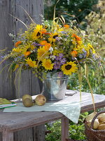 Duftiger Strauß aus Sonnenblumen und Astern in Blechkübel