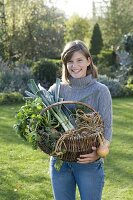 Junge Frau hält Weidenkorb mit Gemüse