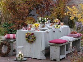 Herbstlich gedeckter Tisch mit Sträussen aus Rosen und Chrysanthemen