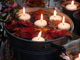 Schwimmkerzen mit Herbstlaub schwimmend in Zinkwanne