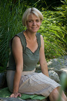 Woman sitting at the edge of the pond with her feet in the water