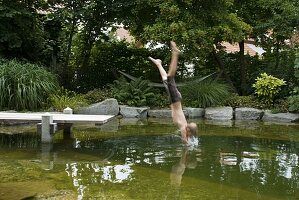 Swimming pond with wooden footbridge bordered with granite blocks