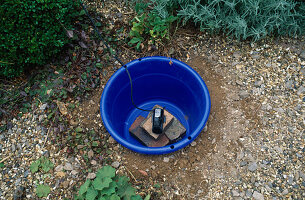 Wasserspiel Schritt für Schritt: Die Pumpe wird auf den Ziegeln im blauen Plastikeimer platziert