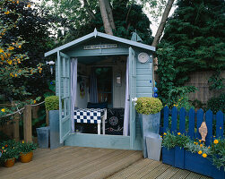 Das 'Upper Deck' mit blauem Gartenhaus und Terrassenbelag aus Holz