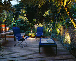 Terrasse mit beleuchteten blauen Liegestühlen, blauem Tisch, Holztisch mit Kerzen, Bambus (Musa Basjoo) und Agave