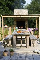 Designer Clare MATTHEWS: Devon GARDEN. OUTDOOR SEATING AREA. Patio with WOODEN TABLE AND BENCHES, COVERED Pergola AND OUTDOOR OVEN / KITCHEN AREA