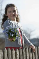 Girl behind fence with bouquet of Myosotis (forget-me-nots)