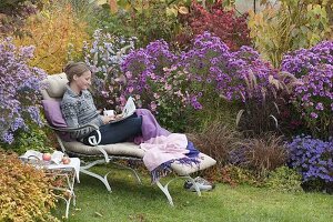 Lie on the autumnal bed with asters and grasses