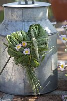 Heart of grasses and bellis (daisies) on old zinc pot