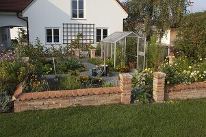 Kleiner Bauerngarten mit Mauer und Gewächshaus