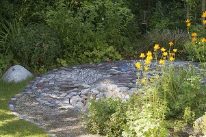 Interestingly paved small terrace between flower beds