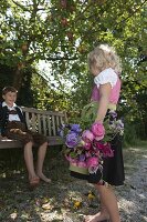 Girl in dirndl with bouquet of pink (roses) and Lathyrus odoratus