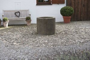 Offener Vorgarten mit Brunnen auf Steckkieselpflaster