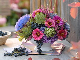 Herbstliches Gesteck in weißer Schale mit Artischocken (cynara), Zinnia