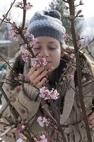 Woman enjoys the scent of Viburnum bodnantense 'Dawn'