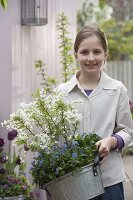 Mädchen mit Exochorda 'Niagara' (Radspiere, Prunkspiere) und Myosotis