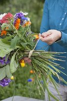 Woman tying a colourful bouquet of summer flowers