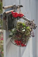 Kleiner Drahtkorb mit Kräutern und Wildfruechten an Türe gehängt