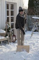 Man pushing snow with snow shovel on terrace