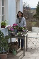 Frau arrangiert rosa Frühlings-Tisch auf der Terrasse