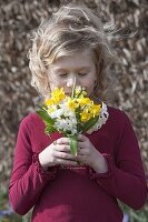 Girl sniffing a small spring bouquet of narcissus (daffodils)