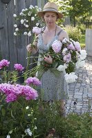 Frau schneidet Paeonia lactiflora (Pfingstrosen) für einen ueppigen Strauss