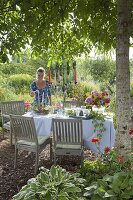 Gedeckter Tisch im Blumengarten unter Walnussbaum