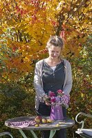 Small seating area with bouquet of asters in front of ironwood tree and ornamental apples