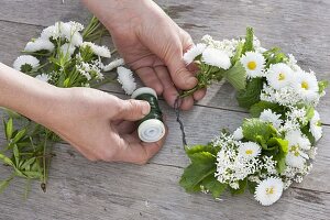 Tying a wreath of daisies and herbs