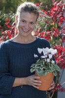 Woman with Cyclamen (Cyclamen) in terracotta pot