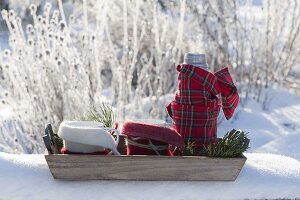 Tablett mit Thermoskanne und Bechern im winterlichen Garten