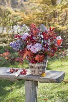 Autumn bouquet with perennials and fruits in basket vase