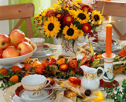 Table decoration with garland tied with hay, ears of corn, physalis (lampion flower), pumpkin