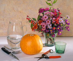 Bouquet with various aster blossoms, pumpkin as vase