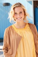 Blonde woman wearing yellow top and brown velour cardigan