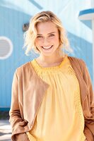 Blonde woman wearing yellow top and brown velour cardigan