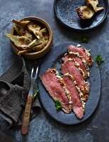 Low-cooked roast beef with a feta and almond crust and artichokes (low carb)