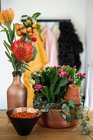 Ornamental apples and needle protea in a vase and Christmas cacti in a decorative bowl