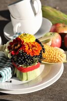 Arrangement of zinnias and dogwood berries wrapped in maize leaves