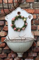 Romantic wreath of ivy leaves and roses hung on old sink