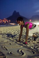 Dunkelhaarige Frau in Designer-Sportkleidung in Startposition am Strand