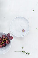 Weintrauben in einer Schale und Kräuterblüte auf Teller