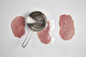 Veal schnitzels being flattened (step by step)